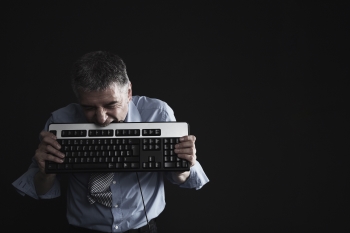 Image of a man with low attention span biting a keyboard