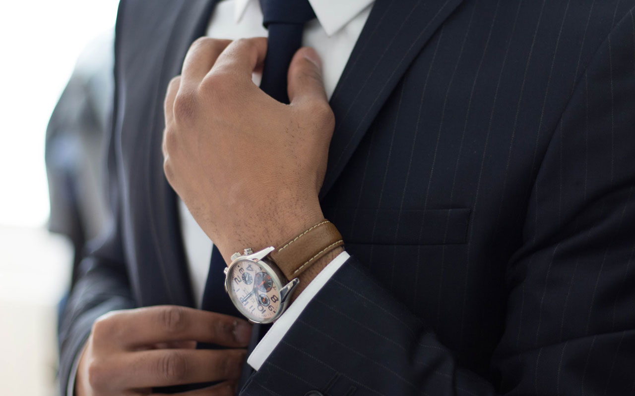 A man adjusts the tie of his suit.