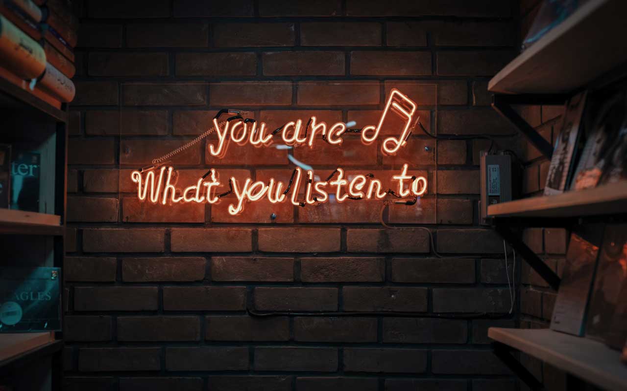 A neon sign that says "you are what you listen to" with an eighth note symbol.