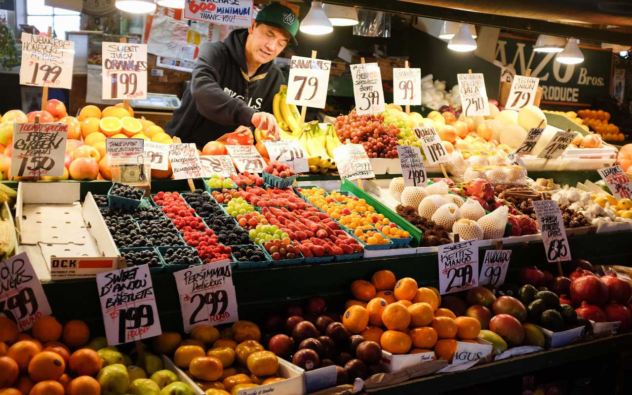 Een man vult op een markt de voorraad producten aan.