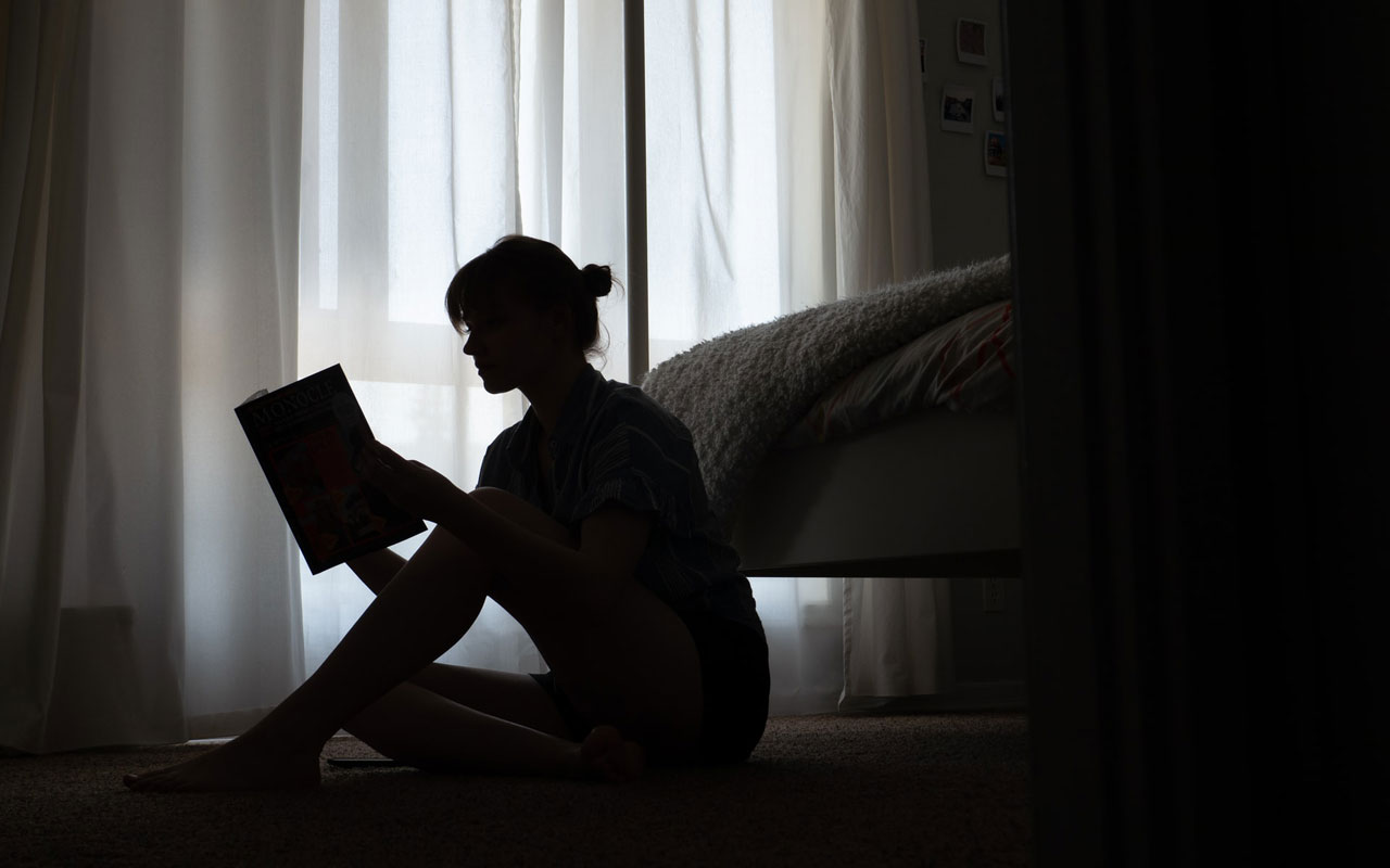 Uma mulher em silhueta, lendo um livro. A leitura é uma das muitas actividades cognitivas para adultos.