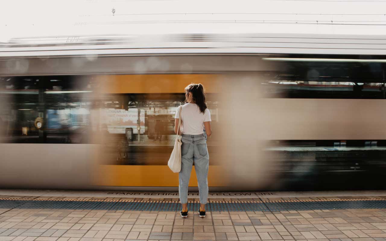 Uma mulher observa a velocidade de um comboio a passar.