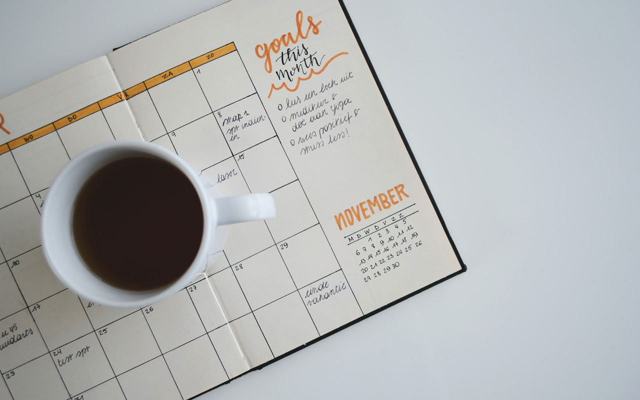 A goals calendar with a cup of coffee sitting on top.