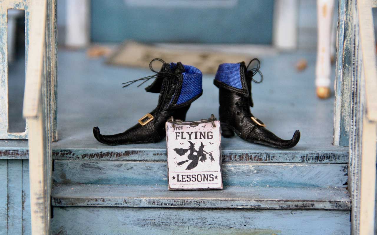 A pair of pointy boots and a "Free Flying Lessons" sign sit on front porch stairs.