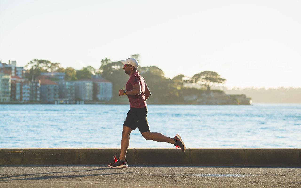 A person runs along a body of water. Keeping healthy through regular exercise is a key part of your memory strategy.