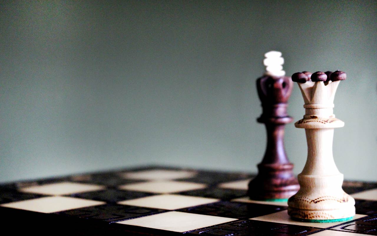 Wooden carved chess pieces on a chess board.