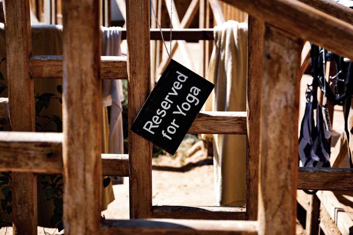 A sign hangs askew on a wooden railing, reading "Reserved for Yoga."
