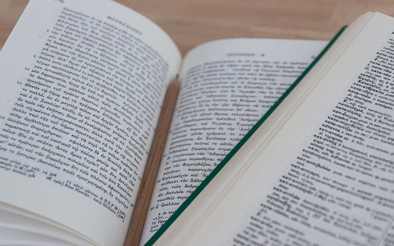 Books in two different languages lay open on a table. Becoming fluent in a language takes time.