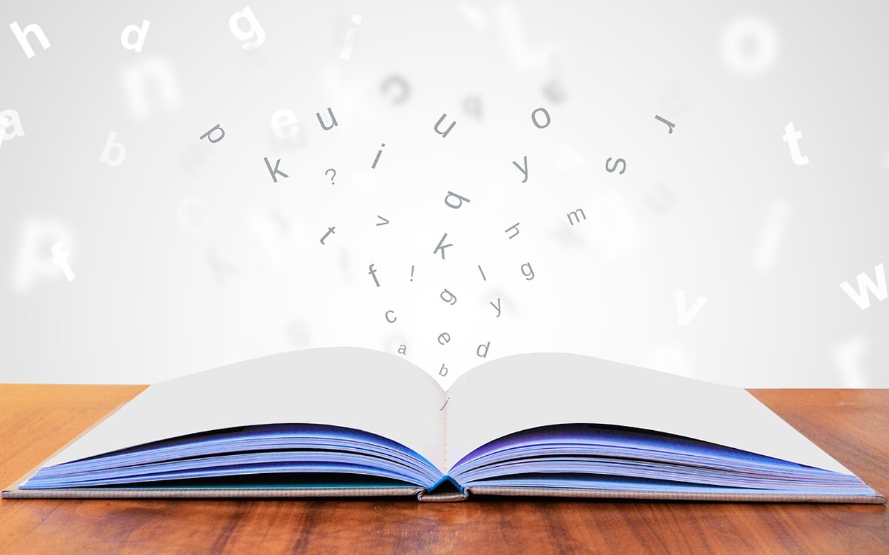 a opened book on a desk and some letters
