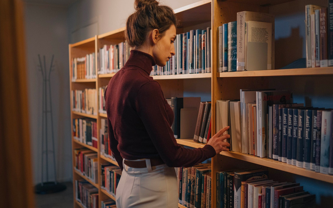a woman looks for books in a library