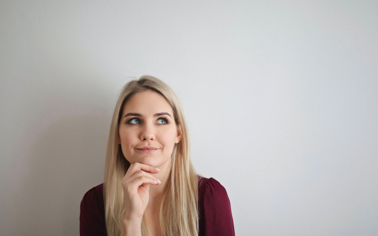 a woman is thinking in front of a white board