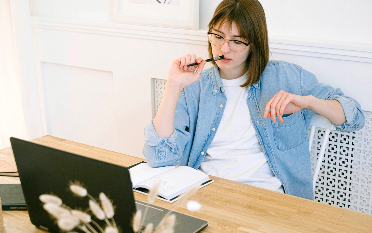 blue shirt woman thinking and writing on her notebook