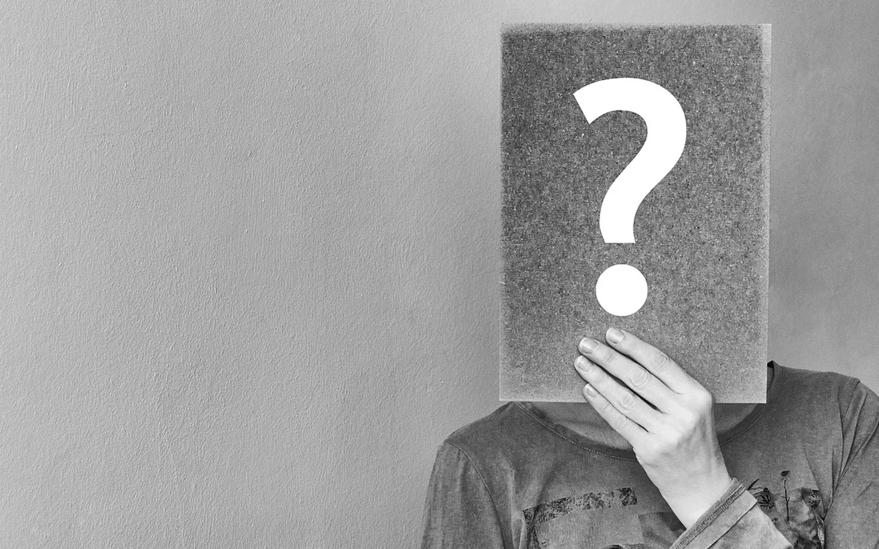 a women covers her face with a question mark