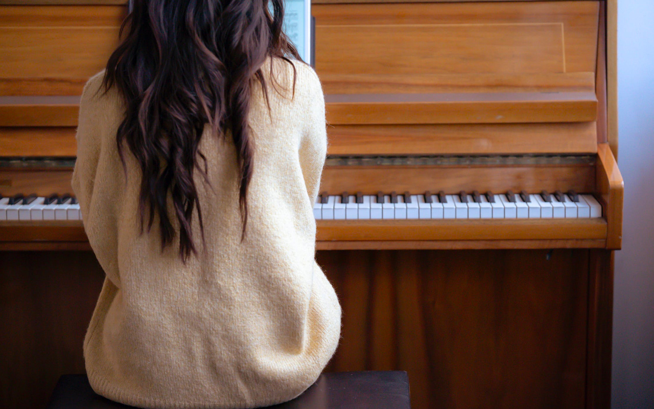 a long hair woman is learning piano